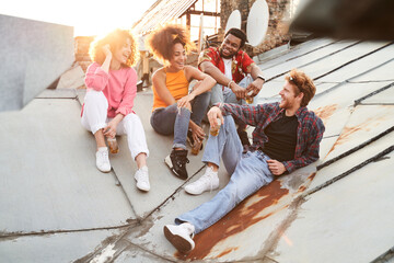 Merry young company relaxing at sunset on roof