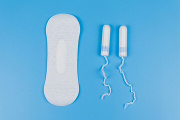 Sanitary pad and tampons on blue background. Top view