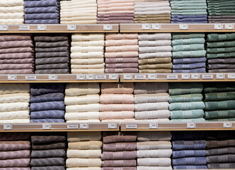 Folded multicolored towels on shelves. Neatly folded clothes. Rack of clothes with warm. Cotton towels neatly folded