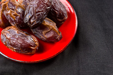 Big luxury dried date fruit in bowls on the dark surface, kurma ramadan kareem concept, close up.