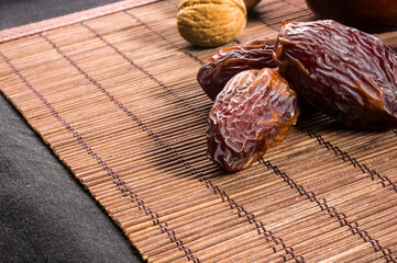 Big luxury dried date fruit on the bamboo mat, kurma ramadan kareem concept, close up.