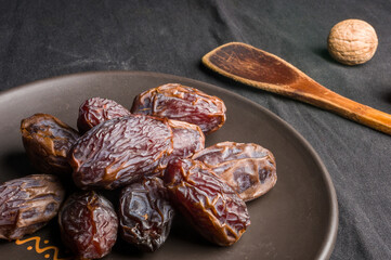 Big luxury dried date fruit in bowls on the dark surface, kurma ramadan kareem concept, close up.