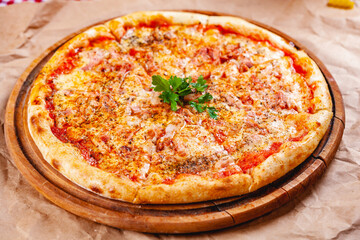 Italian Pizza with bacon, tomatoes and mozzarella cheese on wooden cutting board. Close up