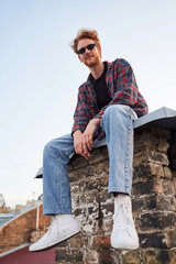 Happy handsome guy sitting on roof alone