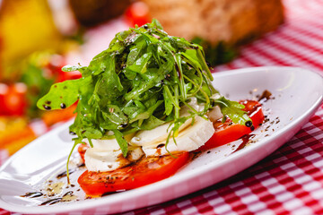 Caprese salad with arugula on white plate. Close up