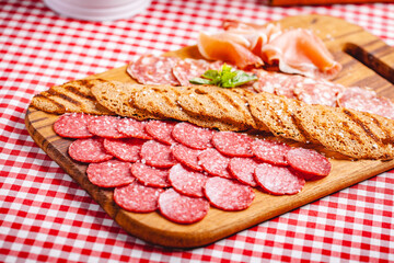 Italian meat and toasted bread on wooden cutting board. Close up