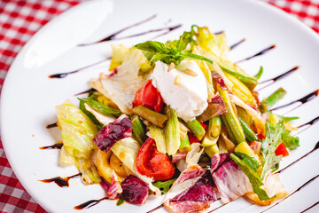 Salad with green beans, tomatoes, bell pepper, ricotta cheese and mixed greens on white plate. Close up