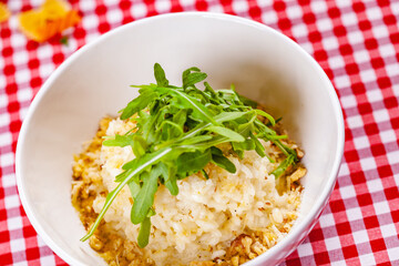 Risotto with gorgonzola, walnuts and arugula on white plate. Close up