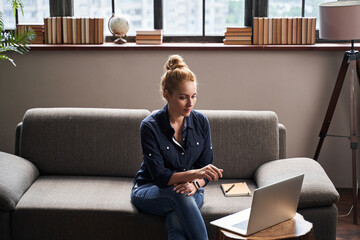 Calm young lady looking at the laptop screen at home