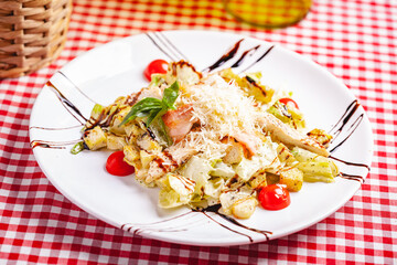 Caesar salad with chicken and bacon on white plate. Close up