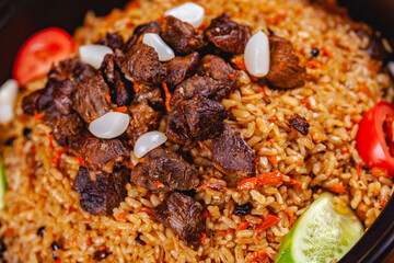 Traditional uzbek pilaf with meat, vegetables and garlic. Close up