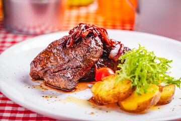 Grilled beef steak served with potato on white plate. Close up