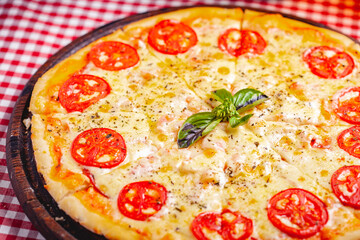 Pizza Margherita (Margarita) with tomatoes and cheese on wooden board. Close up