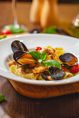 Italian pasta pappardelle with mussels and salmon on white plate. Close up