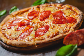 Italian Pepperoni pizza with mozzarella cheese and salami on wooden board. Close up