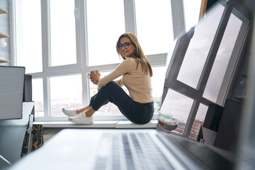 Happy female photographer relaxing with coffee in studio