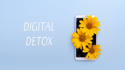 Digital detox concept with inscription. Yellow flowers on a smartphone with copy space. Nature instead of a gadget