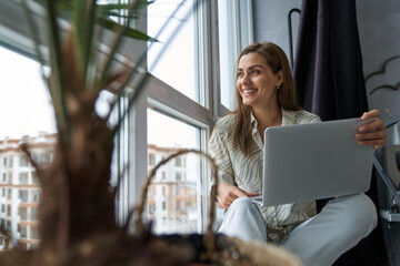 Happy woman with laptop in city apartment