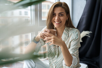 Happy beautiful woman drinking coffee at home