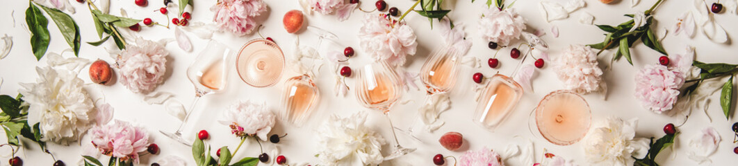 Rose wine variety layout. Flat-lay of rose wine in glasses with flowers and summer fruit over white...