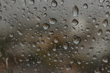 Raindrops on a misted glass with a soft multi-colored background