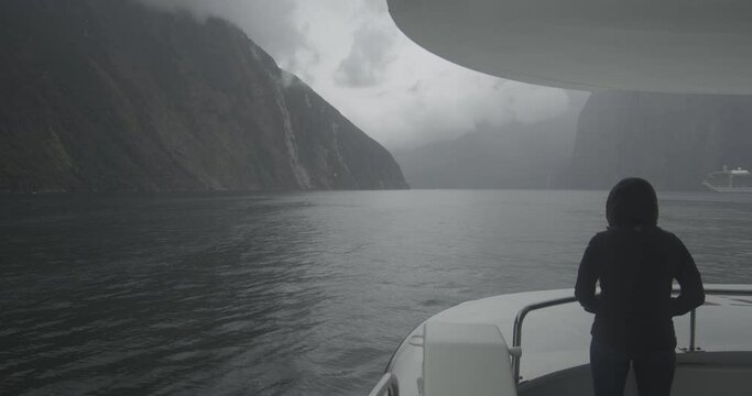 Woman on the bow of boat in Milford Sound New Zealand on a foggy day with waterfall Prores 422 flat color profile with Black Magic Pocket 4k