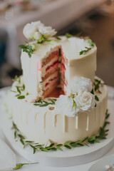 Wedding cake decorated with white roses and green leaves.