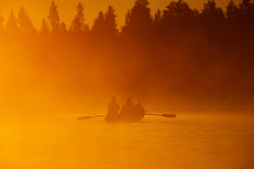 Salmon fishing with rowboat at the sunrise light on misty morning in the Tornio river in Finnish...