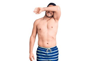 Young handsome man wearing swimwear covering eyes with arm smiling cheerful and funny. blind concept.