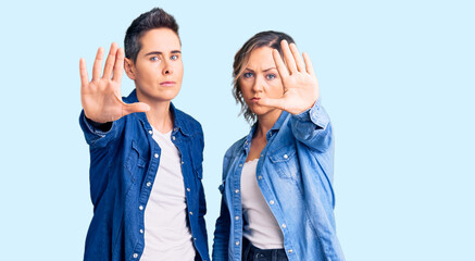 Couple of women wearing casual clothes doing stop sing with palm of the hand. warning expression...