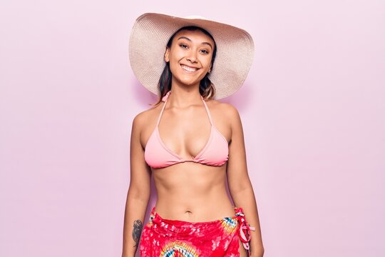 Young woman wearing bikini and hat with a happy and cool smile on face. lucky person.