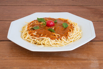 Pasta spaghetti with tomato sauce on a white plate. copy space. Wood background.