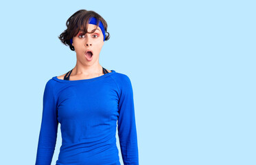 Beautiful young woman with short hair wearing training workout clothes afraid and shocked with surprise and amazed expression, fear and excited face.