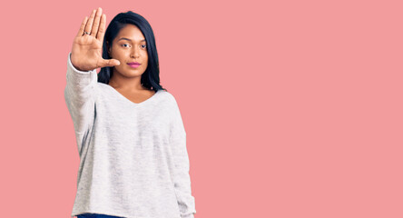 Hispanic woman with long hair wearing casual clothes doing stop sing with palm of the hand. warning...