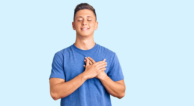 Young handsome hispanic man wearing casual clothes smiling with hands on chest with closed eyes and grateful gesture on face. health concept.