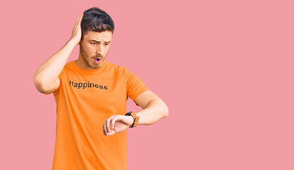 Handsome young man with bear wearing tshirt with happiness word message looking at the watch time...