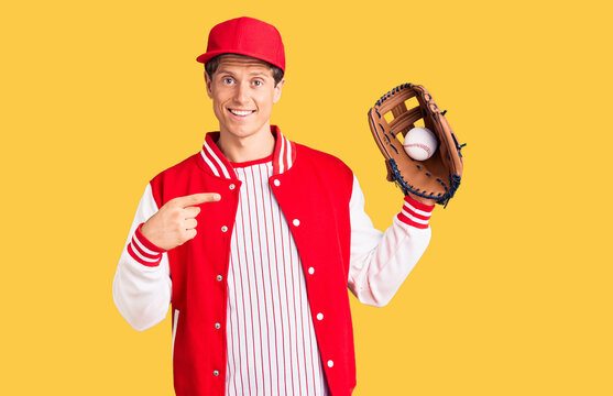 Young handsome man wearing baseball uniform holding golve and ball smiling happy pointing with hand and finger