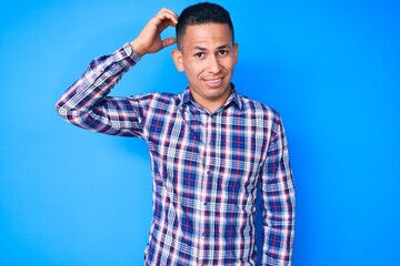 Fototapeta premium Young handsome latin man wearing casual clothes confuse and wonder about question. uncertain with doubt, thinking with hand on head. pensive concept.