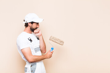 young painter bearded man thinking and holding a roller.