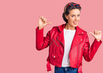 Young beautiful woman wearing red leather jacket looking confident with smile on face, pointing...