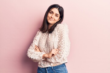 Young beautiful girl wearing casual clothes smiling happy and confident. Standing with smile on face and arms crossed over isolated pink background
