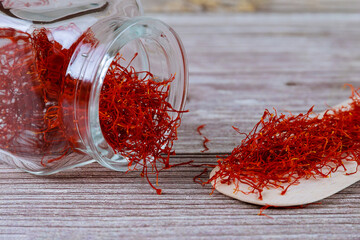 Saffron spice in a glass bottle and on a wooden spoon.
