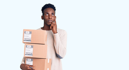 Young african american man holding delivery package serious face thinking about question with hand...