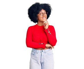 Young african american girl wearing casual clothes and glasses looking confident at the camera smiling with crossed arms and hand raised on chin. thinking positive.