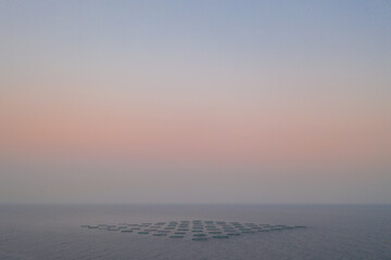 sunrise in the sea with fog and a formation of shapes in the water in long distance