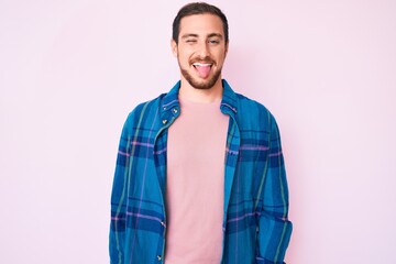 Fototapeta premium Young handsome man wearing casual clothes sticking tongue out happy with funny expression. emotion concept.