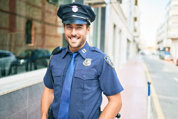 Young handsome hispanic policeman wearing police uniform smiling happy Standing with smile on face...