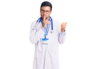 Fototapeta na wymiar Young hispanic man wearing doctor uniform and stethoscope asking to be quiet with finger on lips pointing with hand to the side. silence and secret concept.
