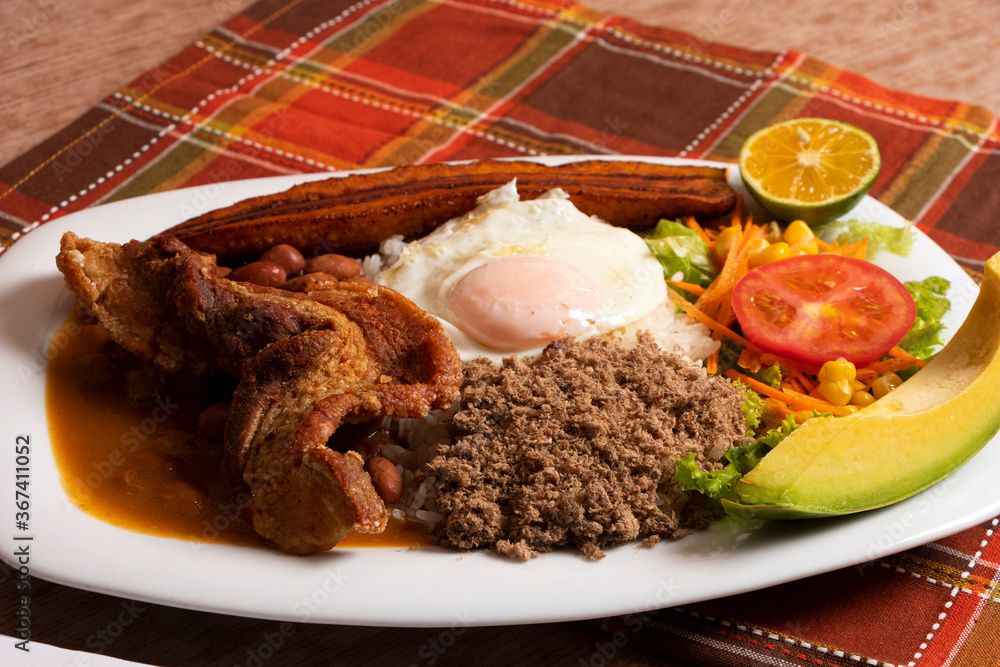 Wall mural bandeja paisa plato tradicional en medellin con carne de cerdo arroz huevo plátano limon tomate agua