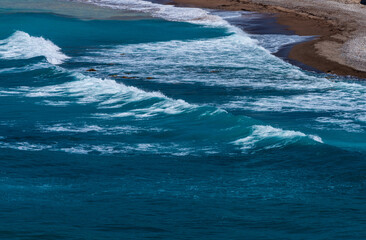 Fototapeta na wymiar blue waves on the beach making an s line with brown sand